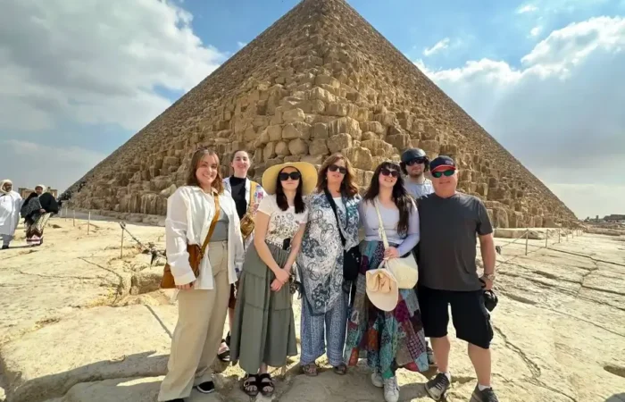 A family standing in front of the Great Pyramid of Giza during a guided tour of the pyramids in Egypt.