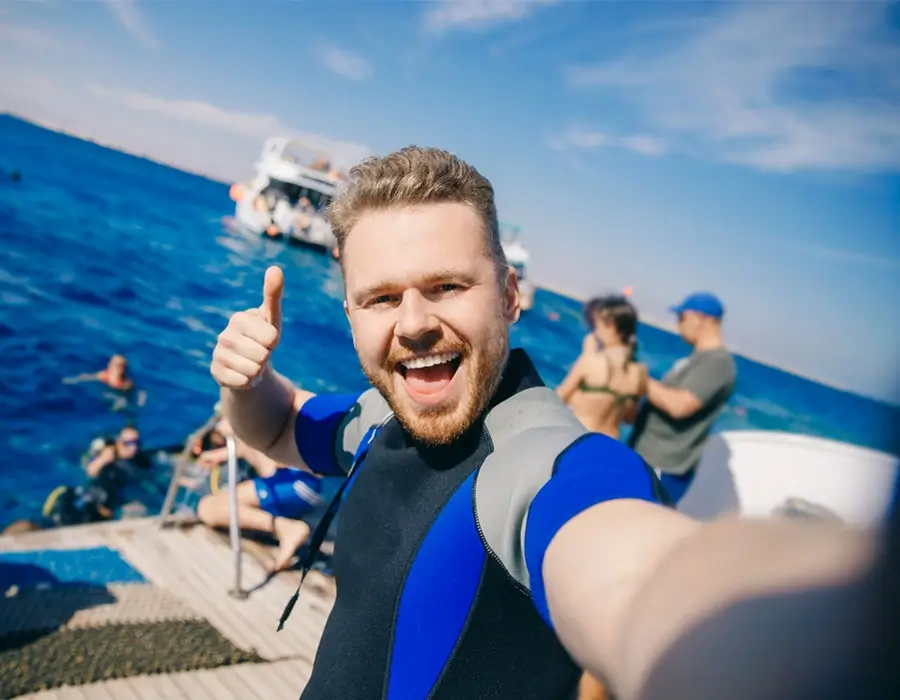 Happy tourist in a wetsuit giving a thumbs up during a Red Sea snorkeling trip in Egypt.