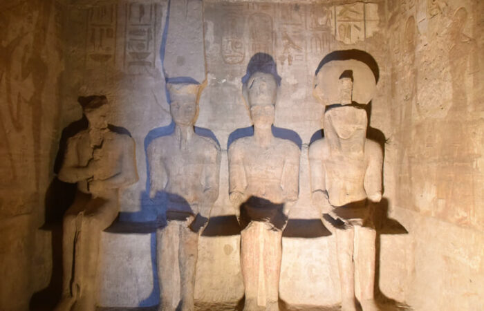 Sun's rays illuminate the seated Amun-Ra, Horakhty, and Ramses II statues in the inner sanctuary of Abu Simbel Temple