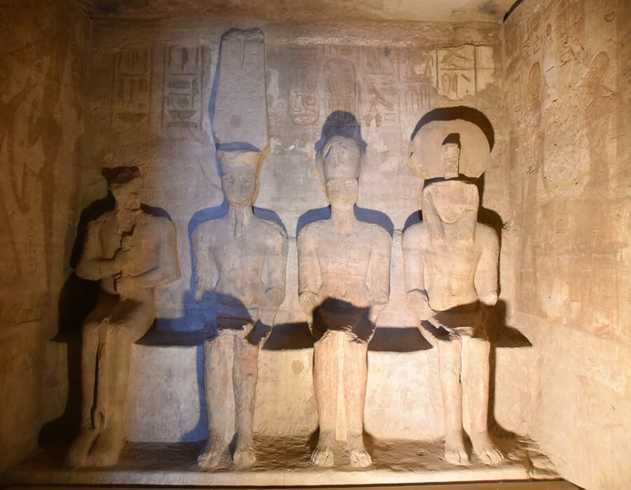Sun's rays illuminate the seated Amun-Ra, Horakhty, and Ramses II statues in the inner sanctuary of Abu Simbel Temple