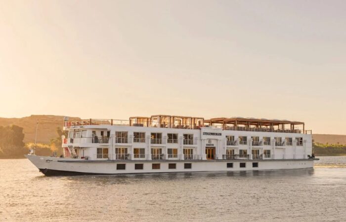 A cruise ship navigating the Nile River with a clear sky in the background.