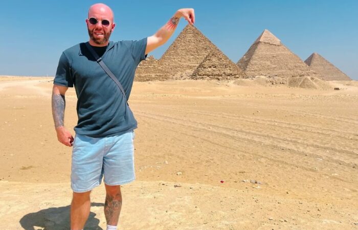 Tourist posing in front of the Giza Pyramids, one of the top attractions in Giza, Egypt.