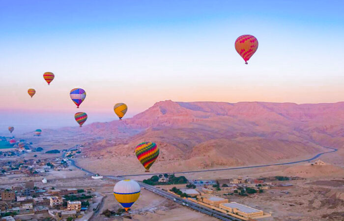 Colorful hot air balloons floating over the West Bank of Luxor at sunrise for an Egypt tour