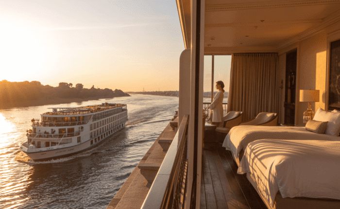 Luxury Nile cruise ship passing by a balcony with elegant accommodation on a sunset river view